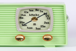Ein altes grünes Radio mit einer Skala, die mit Zahlen und Text markiert ist, steht auf einem weißen Tisch.
