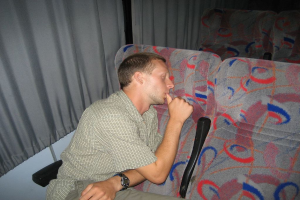 Eine Person liegt auf einem Stuhl mit anderen Stühlen und Vorhängen im Hintergrund.