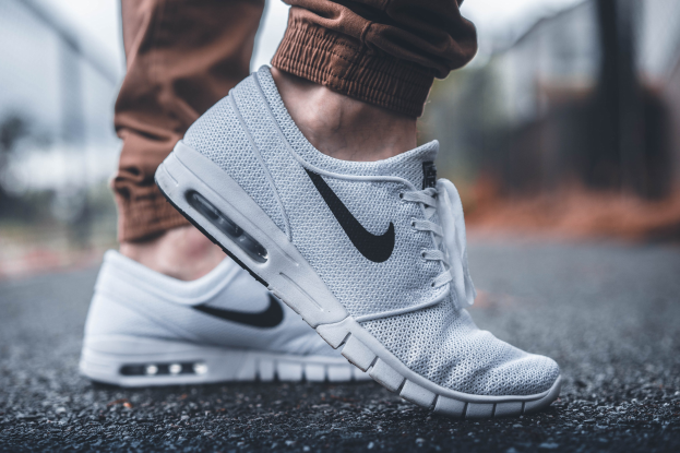 Eine Person in schwarzen und weißen Nike SB Stefan Janoski Max-Schuhen in Wolf Grau vor einem unscharfen, träumerischen Hintergrund.