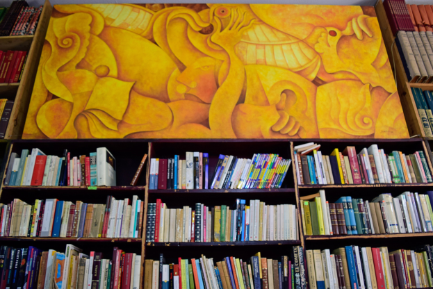 Ein Bücherregal voller ordentlich arrangierter Bücher und ein Gemälde an der Wand im Hintergrund.