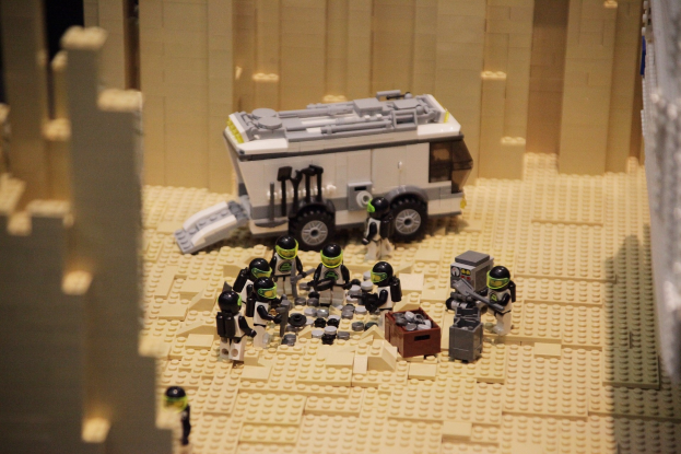 Lego-Modell einer Star Wars-Szene mit einem Fahrzeug im Vordergrund und einer Wand im Hintergrund sowie einigen verstreuten Spielzeugen.