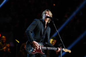 Keith Urban performs auf der Bühne im Joint in Las Vegas, spielt eine Gitarre mit einem Mikrofon vor sich und Musiker im Hintergrund, unter dunkler Beleuchtung.