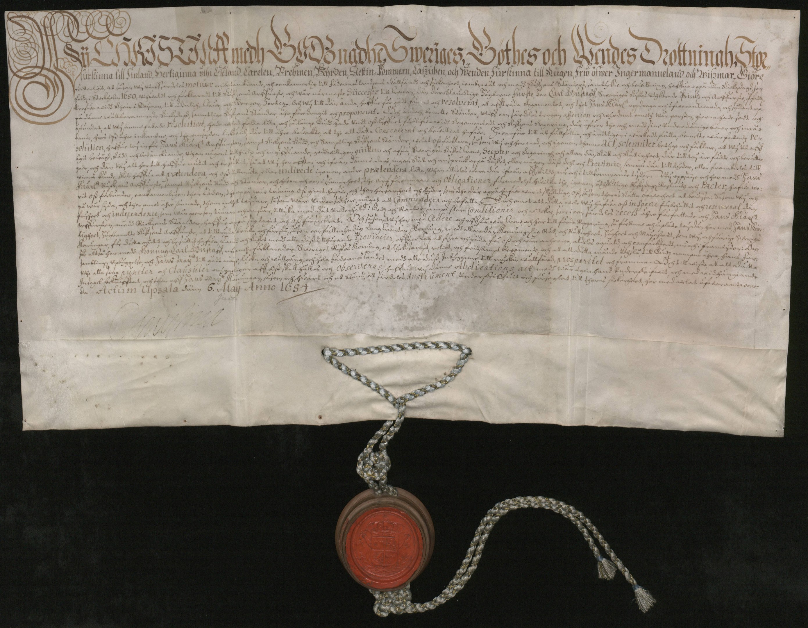 Altes Dokument mit rotem Wachssiegel an einer Kette befestigt, das wie ein Vertrag mit sichtbarem Text aussieht.