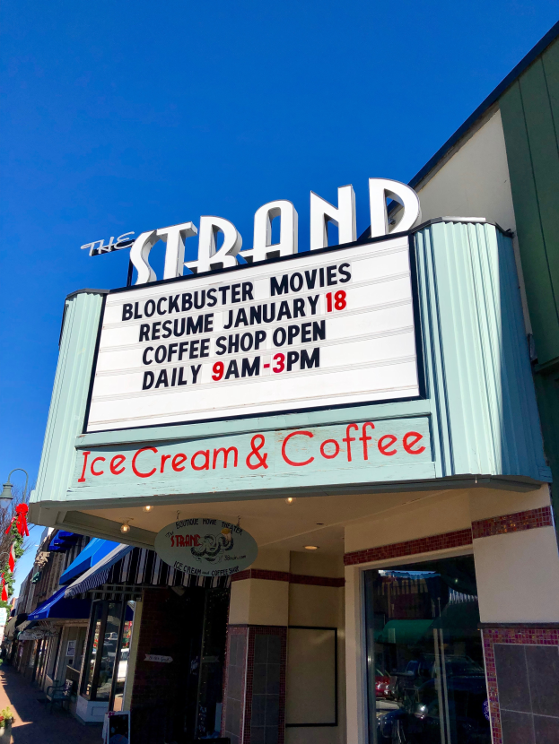 Der Strand-Blockbuster-Kino startet am 18. Januar Kaffeebar mit einem Namensschild, einem Straßenschild, einer Gruppe von Bäumen, einigen Topfpflanzen und einem bewölkten Himmel.