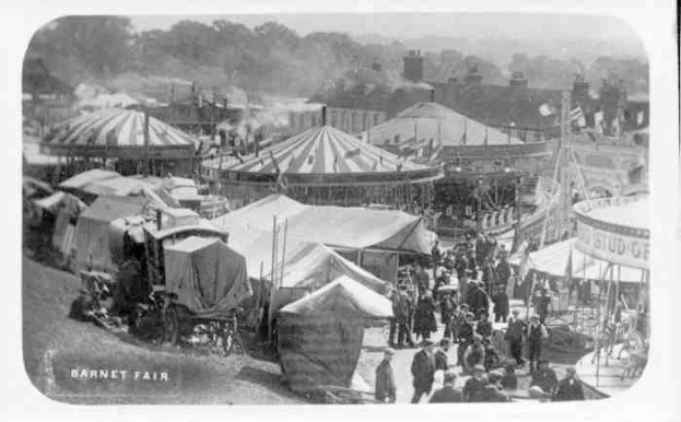 Schwarzes und weißes Foto von Barnet Fair in London, England, mit Zelten, Menschen, Karren, Pfählen, Bäumen und Gebäuden im Hintergrund.