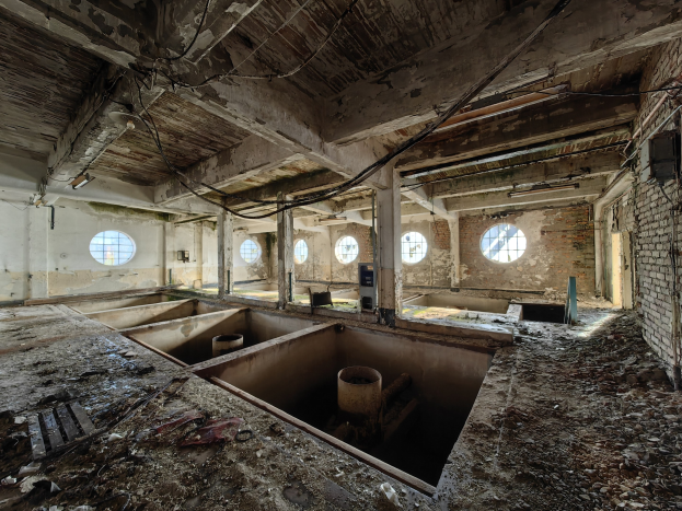 Verlassenes Gebäudeinnere im Sperrgebiet von Tschernobyl mit verstreuten Trümmern, freiliegenden Wänden, Decke und strukturellen Elementen.