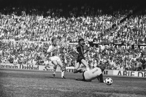 Schwarzes und weißes Foto von Fußballspielern im Einsatz auf einem Feld mit Zuschauern im Hintergrund und einer "Bundesliga 1978-79 Ajax 1-1 Hannover 96"-Aufschrift.