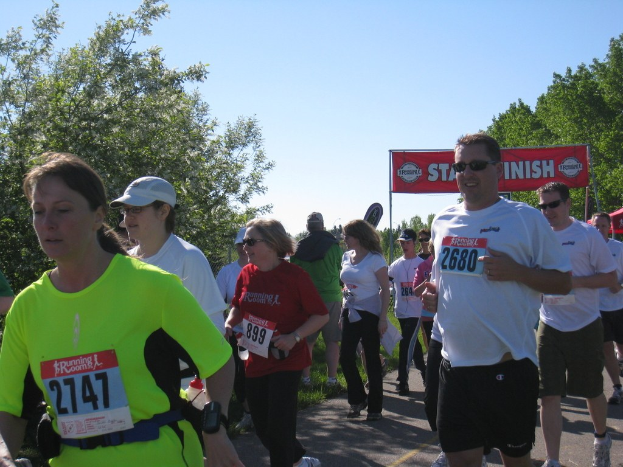 Gruppe von Kindern, die in einem Marathonlauf mit einem roten Banner und Bäumen im Hintergrund laufen.