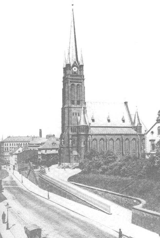 Schwarzes und wei├čes Foto einer Stra├če mit der St. Peter Kirche in Wiesbaden im Hintergrund, flankiert von Geb├Ąuden, B├Ąumen, Fahrzeugen und Passanten.