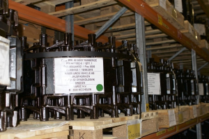 Ein Lagerhaus voller Metallobjekte auf Holzpaletten, jedes mit einem Aufkleber, der Teil eines Verteilergeschäfts zu sein scheint, mit verschiedenen sichtbaren Komponenten.