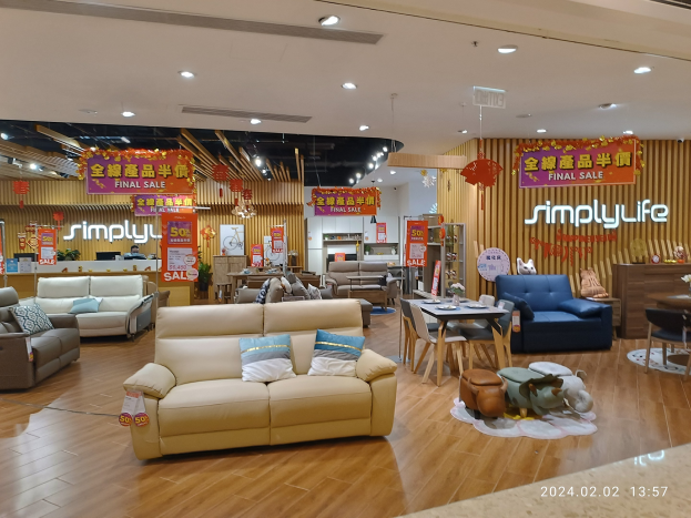 Ein Einrichtungshaus-Innenraum mit Sofas, Tischen, Stühlen, Hockern, Deckenleuchten und Texttafeln, mit einem Wasserzeichen in der rechten unteren Ecke.