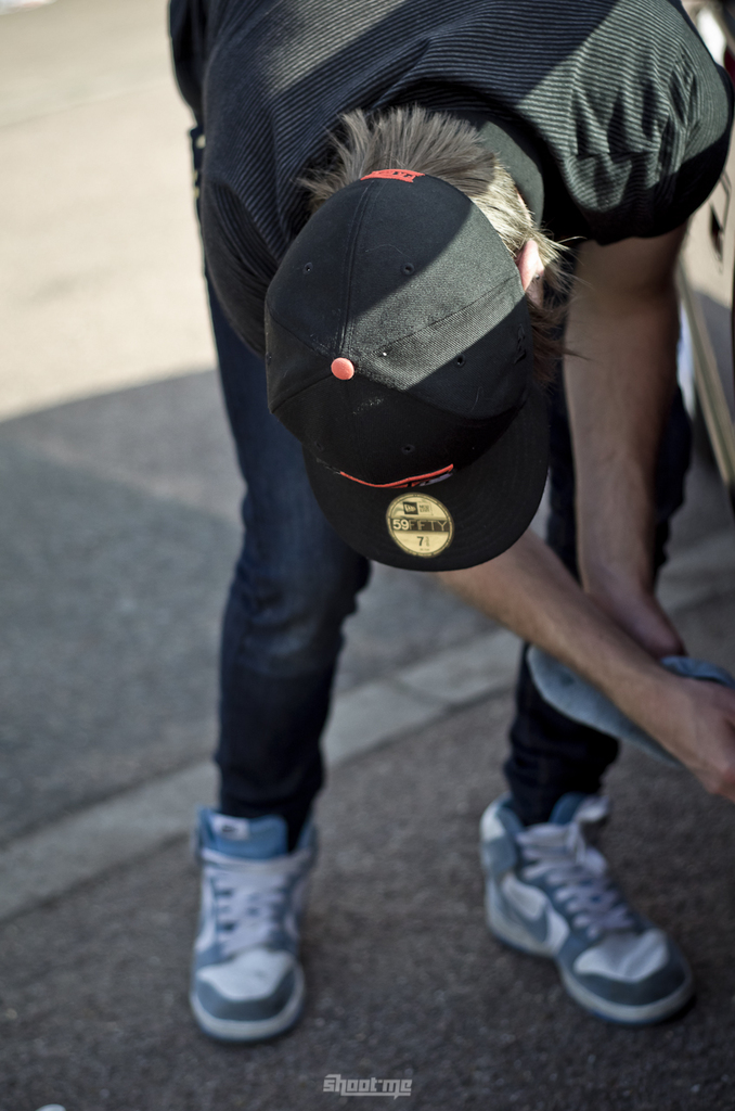 Eine Person mit einer schwarzen Mütze, schwarzem T-Shirt, Jeans und Schuhen, die auf einem Weg steht.