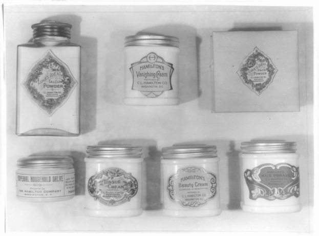 Schwarzes und weißes Foto eines Regals mit ordentlich angeordneten Cremetöpfchen, jedes mit einer anderen Aufschrift beschriftet.