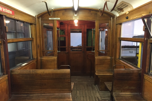 Ein Holz-Sitzwagen-Innenraum in Berlin, Deutschland, mit Holzsitzen, Glasfenstern, Türen, Lampen und anderen Gegenständen.
