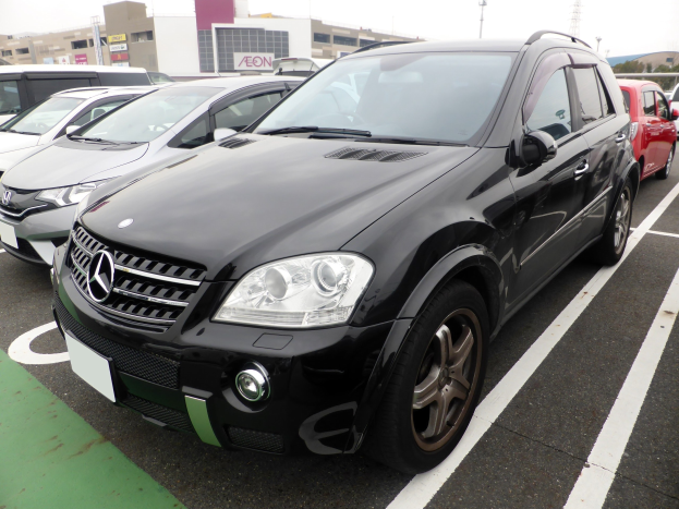 Schwarzer Mercedes-Benz ML 350 CDI BlueEfficiency auf einem Parkplatz mit Gebäuden, Masten, Bäumen und einem klaren blauen Himmel geparkt.