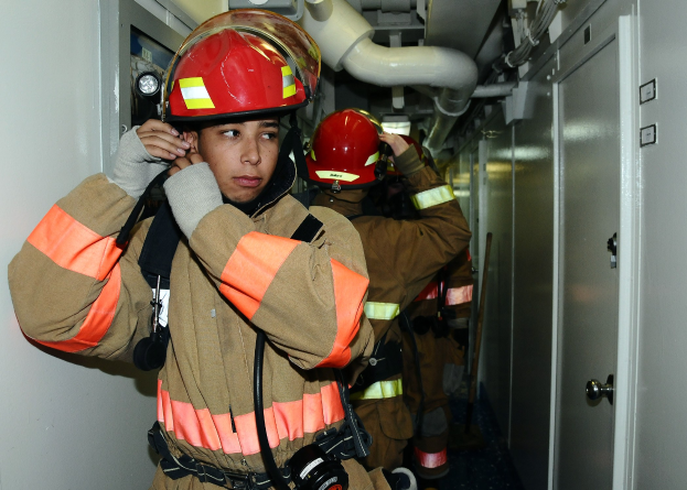 Feuerwehrleute in Uniform in einem Raum mit Rohren und Geräten während eines Trainings.