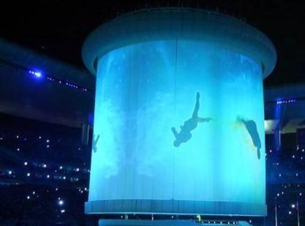 Großes beleuchtetes Stadiondisplay mit einer Personendarstellung während der Eröffnungszeremonie der Olympischen Sommerspiele 2012 nachts.