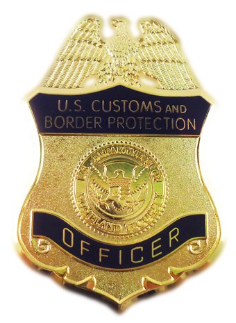 Goldene Plakette mit der Aufschrift "U.S. Customs and Border Protection Officer" auf weißem Hintergrund.