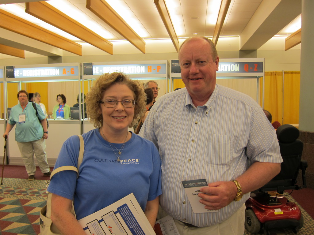 Menschen, die auf einem Boden mit einem Rollstuhl und einer Wand im Hintergrund, Decke und Lichter oben stehen.