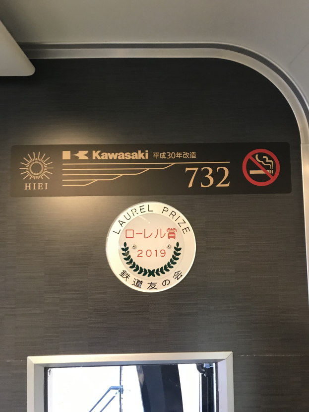 Wand mit einem Schild, das "Kawasaki 732" lautet, und einem Glasfenster auf der rechten Seite.