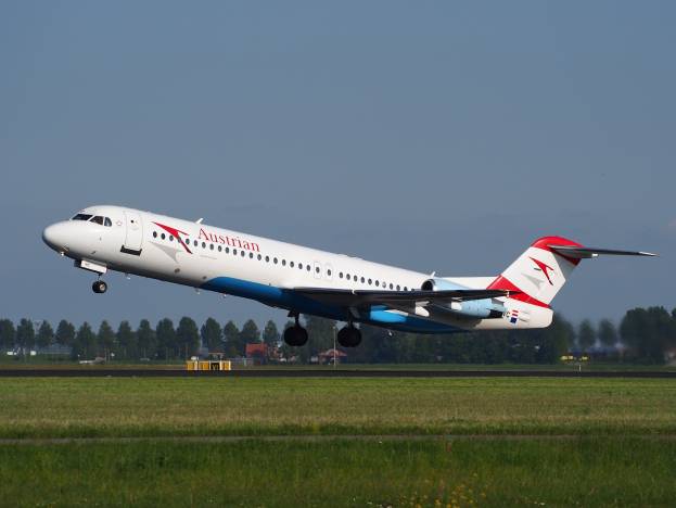 Austrian Airlines Embraer ERJ-190 Flugzeuge beim Start vom Frankfurt Airport, mit grünem Gras, Bäumen, Gebäuden und Himmel im Hintergrund.