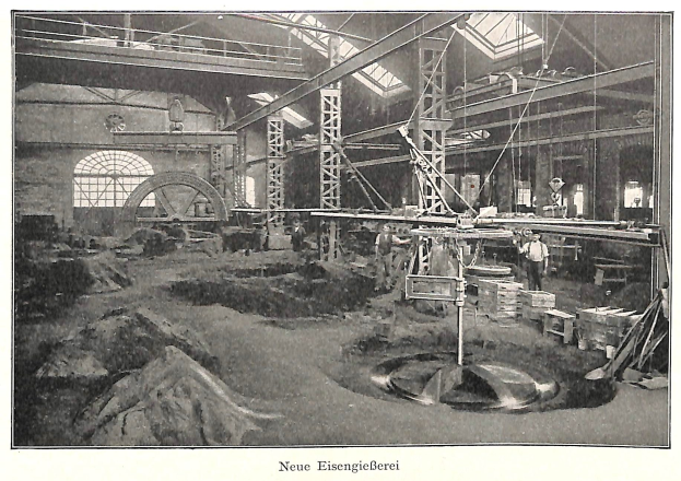Schwarze und weiße Fotografie eines Fabrikinneren mit Arbeitern, die Maschinen bedienen, Metallstangen und -pole, beschriftet mit "Neue Eisenglebeerei, die erste Fabrik in Deutschland" unten.
