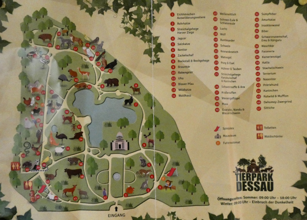 Detailierte Karte eines Parks mit verschiedenen Tieren, Gebäuden und Merkmalen, umgeben von üppigen grünen Bäumen.