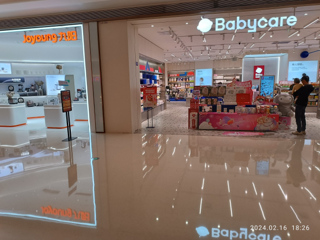 Ein Babyladen in einem Einkaufszentrum mit Menschen, Spielzeugen, Regalen, Schildern, einem Bildschirm und Deckenleuchten, befindet sich im Mall of Asia.