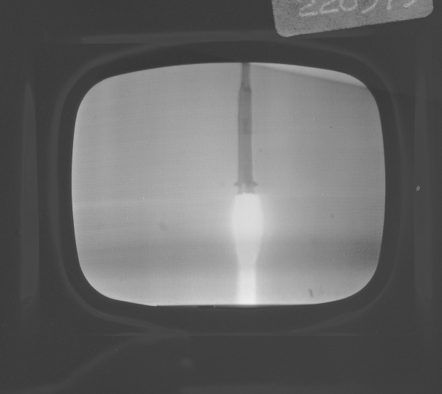 Schwarz-weiß-Foto eines Fernseherbildschirms mit Raketenstart durchs Fenster und Text oben.