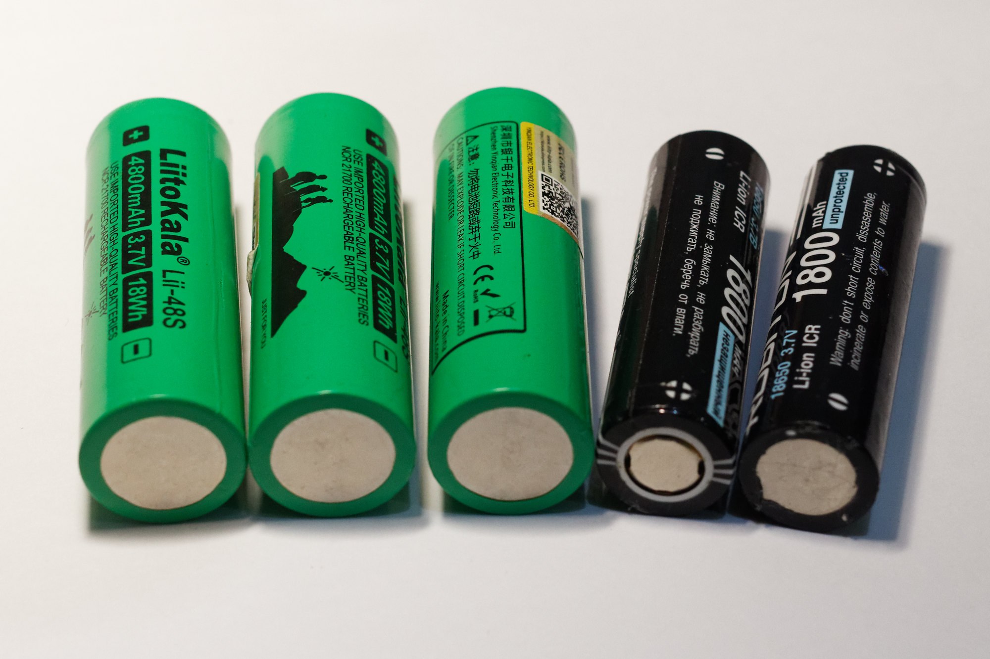 Vier grüne Li-Ion-Wiederaufladbare Batterien mit der Bezeichnung "Li-Ion" und "18650" nebeneinander auf einer weißen Oberfläche.