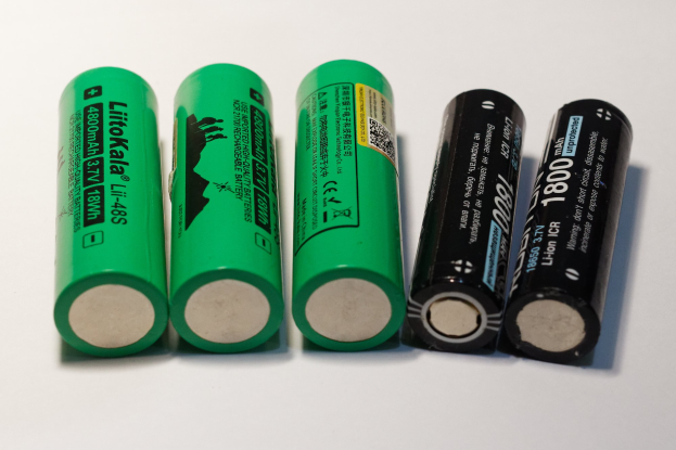 Vier grüne Li-Ion-Wiederaufladbare Batterien mit der Bezeichnung "Li-Ion" und "18650" nebeneinander auf einer weißen Oberfläche.
