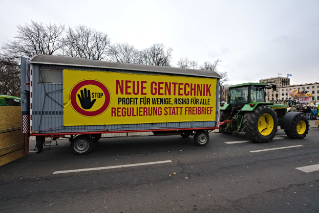 Truck with a sign driving down a street in a demonstration, surrounded by people, trees, buildings, and a clear blue sky in Germany.