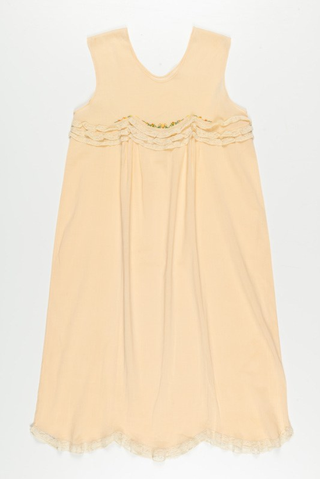 Ein cremefarbenes Nachthemd mit zarter Spitzenborte am Halsausschnitt, aus weichem, leichtem Stoff mit einem leichten Schimmer.