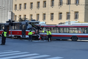 Eine rote und weiße Tram, die in einen Unfall auf der Straße verwickelt ist, mit ein paar Menschen in der Nähe und einem Gebäude im Hintergrund.