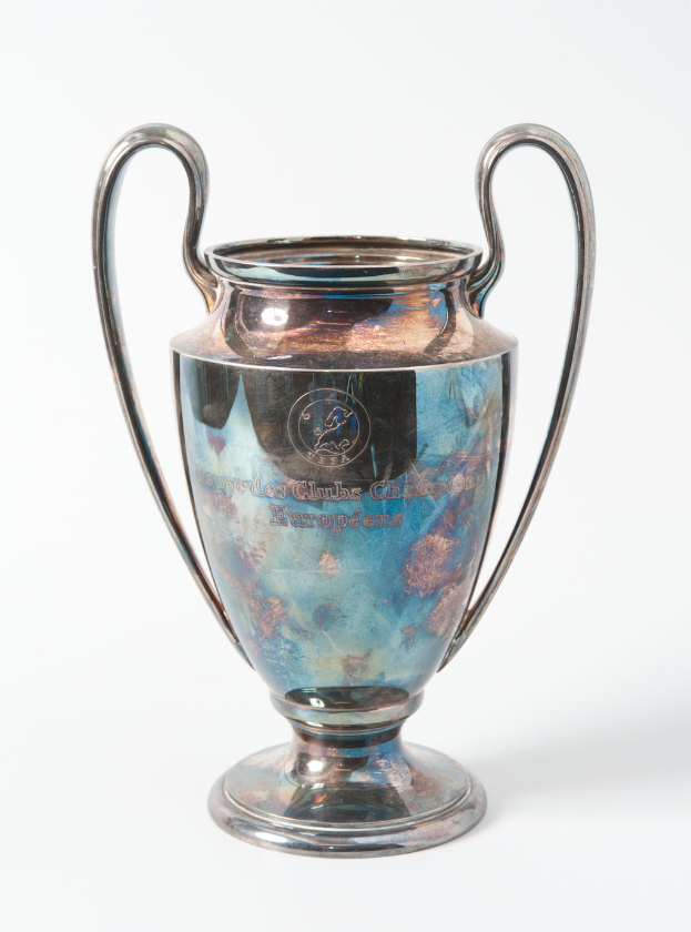 Der UEFA-Champions-League-Pokal, ein stählerner Pokal mit zwei Griffen und einer blauen und silbernen Farbgebung, mit der Inschrift "UEFA Champions League", vor einem weißen Hintergrund.
