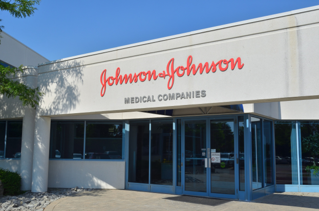 Das Johnson & Johnson Medical Companies-Gebäude mit Glaswänden und -türen, Text an der Wand, Steinen, Pflanzen und einem Baum auf der linken Seite vor einem klaren blauen Himmel.