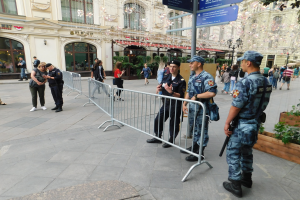 Polizeibeamte in Uniform stehen hinter Barrieren und schauen auf eine Menge, einige halten Waffen, mit Schildern und Gebäuden im Hintergrund während einer Anti-Terror-Operation in Wien, Österreich.