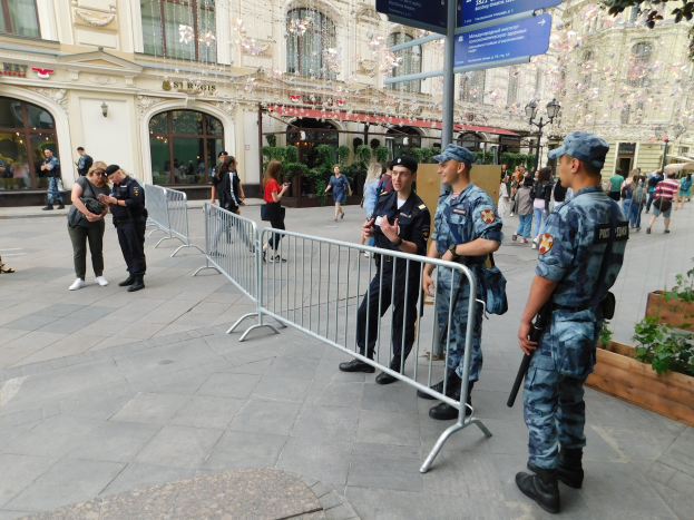Polizeibeamte in Uniform stehen hinter Barrieren und schauen auf eine Menge, einige halten Waffen, mit Schildern und Gebäuden im Hintergrund während einer Anti-Terror-Operation in Wien, Österreich.