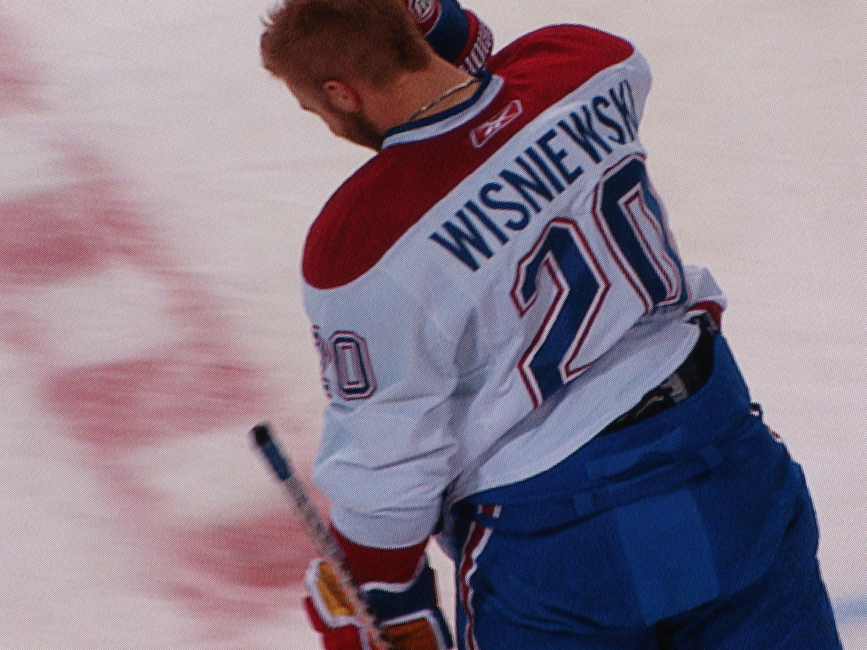 Professioneller Eishockeyspieler mit einem "Wisniewski"-Trikot, der einen Hockey-Schläger auf dem Eis hält und konzentriert schaut.